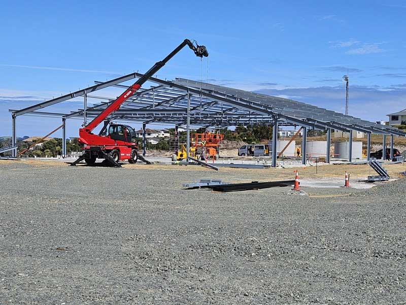 Construction site with red crane and metal framework.